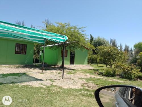een groen huis met een blauwe luifel ervoor bij Hospedaje El TaTa in Colonia Las Rosas