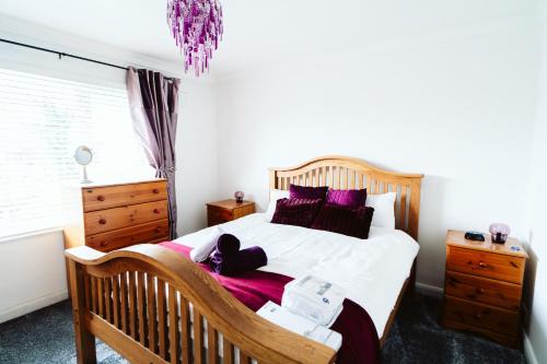 sypialnia z drewnianym łóżkiem z fioletowymi poduszkami w obiekcie Turves Place, 3 Bedroom property/near MCR Airport w mieście Cheadle Hulme