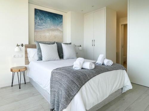 Tyba Deluxe Apartment في أليكانتي: غرفة نوم بسرير ابيض كبير عليها مناشف