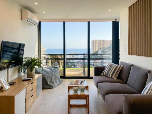 Tyba Deluxe Apartment في أليكانتي: غرفة معيشة مع أريكة ونافذة كبيرة