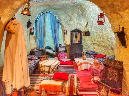 a room with beds and a fireplace in a cave at Grotte Thami in Bhalil