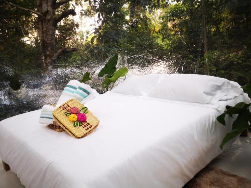 Una cama blanca con una caja encima. en Glamping Amazonas, en Leticia