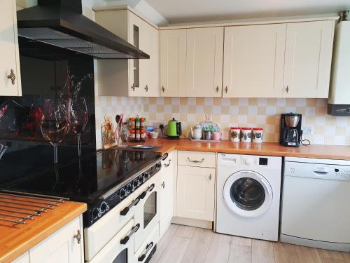 a kitchen with white cabinets and a washer and dryer at Rabbit Haven - 4 minutes from Bicester Village! in Bicester