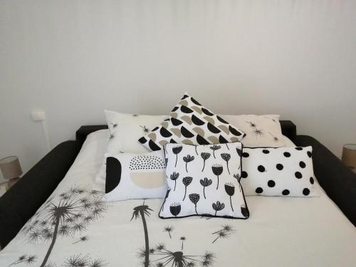 Una cama con almohadas blancas y negras. en bel appartement en résidence "bois doré" avec piscine et mini golf privés proche centre ville et Stade Rochelais, en La Rochelle