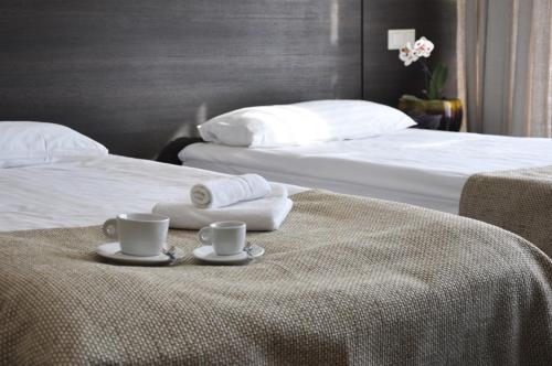 a hotel room with two beds with cups and towels at Hotel Babilonas in Kaunas