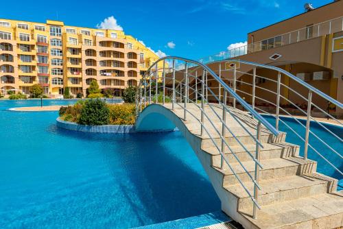 uma ponte sobre uma piscina com edifícios em Menada Grand Resort Apartments em Aheloy
