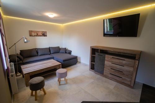 een woonkamer met een bank en een flatscreen-tv bij Das Appartment im Gästehaus im Rittergut Keulrod in Bischofrod