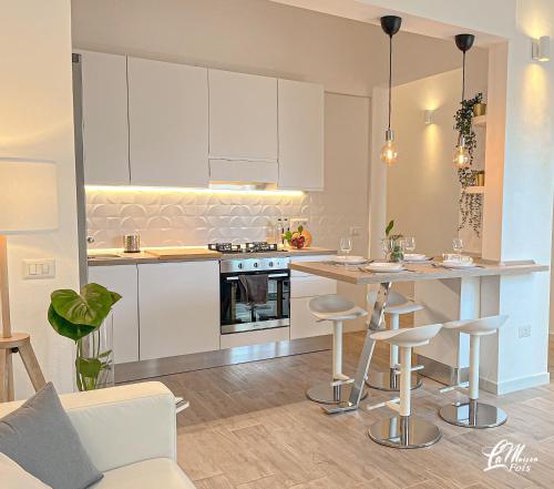 a kitchen with white cabinets and a island with bar stools at La Maison Fois - Appartamento Quartucciu in Quartucciu