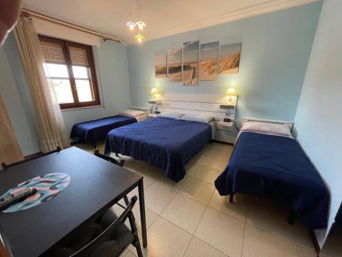 a room with two beds and a table and a dining room at B&B Su Fassoi in Santa Giusta
