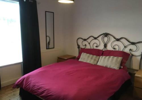 a bedroom with a large pink bed with red pillows at 4 Bedroom House For Corporate Stays in Kettering in Kettering