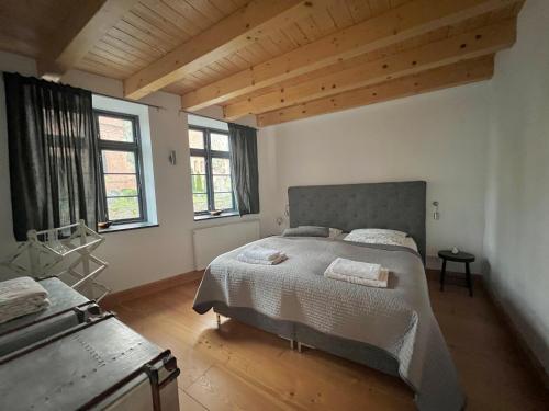 a bedroom with a large bed and two windows at Historisches Pastorat - Villa Mika in Fehmarn