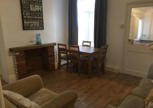 ein Wohnzimmer mit einem Tisch, Stühlen und einem Kamin in der Unterkunft 4 Bedroom House For Corporate Stays in Kettering in Kettering