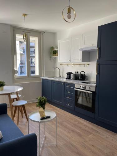 eine Küche mit blauen Schränken und eine Küche mit einem Tisch in der Unterkunft L'Appartement Bleu - Logement cosy - Cœur de ville in Douai