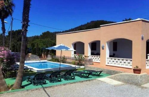 a house with a swimming pool with chairs and an umbrella at Can Pep Ramon 2 in Sant Francesc de s'Estany