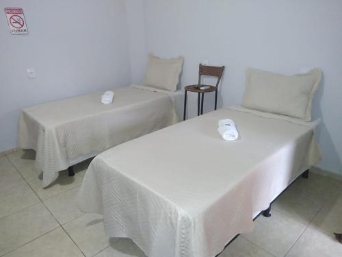 two beds with white linens in a room at pousada jalapão arco iris in Mateiros