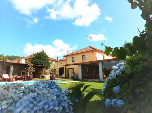 ein Haus mit einem Hof mit blauen Blumen in der Unterkunft Casa de Penim in Paredes de Coura