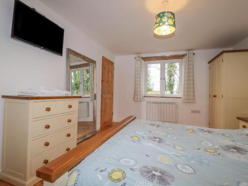 a bedroom with a bed and a dresser and a television at Vine Cottage in Saint Ewe