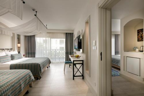 a hotel room with two beds and a desk at Limak Cyprus Deluxe Hotel in Iskele