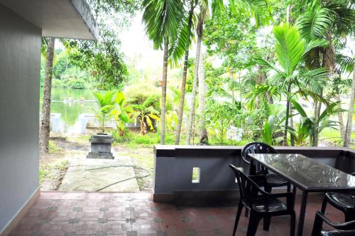 a patio with a table and chairs and a pond at Muralee's Riverside Villa in Kochi in Cochin