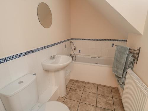 a white bathroom with a toilet and a sink at No 1 Low Hall Cottages in Scalby