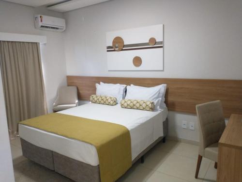 a bedroom with a bed and a desk and a chair at Regional Plaza Hotel Event Park in Jales