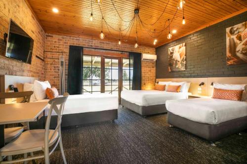 a bedroom with two beds and a table and a dining room at Nightcap at Macquarie Inn in Dubbo
