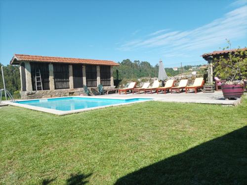 a swimming pool in a yard with chairs and a house at Casa de Penim in Paredes de Coura