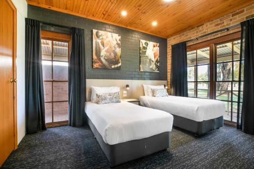 two beds in a room with windows at Nightcap at Macquarie Inn in Dubbo