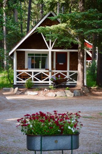 a house with a porch with flowers in front of it at Johnston Canyon Lodge & Bungalows in Castle Junction