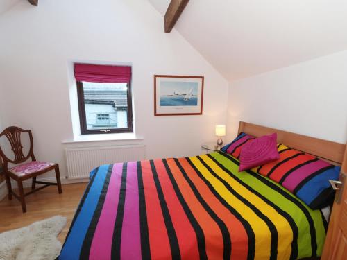 a bedroom with a colorful striped bed and a chair at Mill Bridge Cottage in Castleton