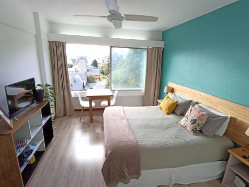 1 dormitorio con 1 cama con pared azul en Nothofagus Apartments en San Carlos de Bariloche