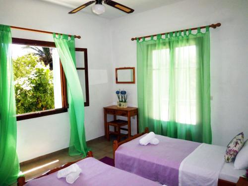 a room with two beds and a window with green curtains at Paraskevi Apartments in Ipsos