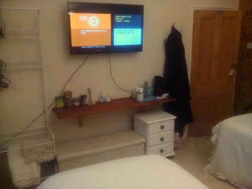 1 dormitorio con TV en la pared y vestidor en The Principality 2 Singles Bedroom en Cardiff