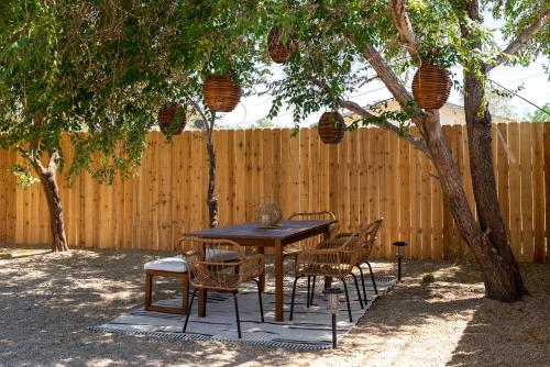 a wooden table and chairs under a tree with a fence at Red Rock - Desert feel - Game Room in Joshua Tree