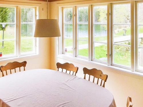 ein Esszimmer mit einem großen weißen Tisch und Fenstern in der Unterkunft Holiday home ÅSBRO II in Åsbro