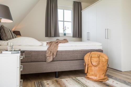 FuhlendorfにあるFerienhaus Schilfrohrsaenger 54のベッドルーム1室(ベッド1台付)、床にリュックサックが備わります。