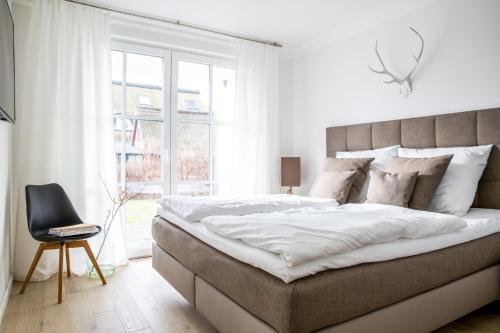 a white bedroom with a large bed and a chair at Ferienwohnung Duene 2_2 in Groß Kirr