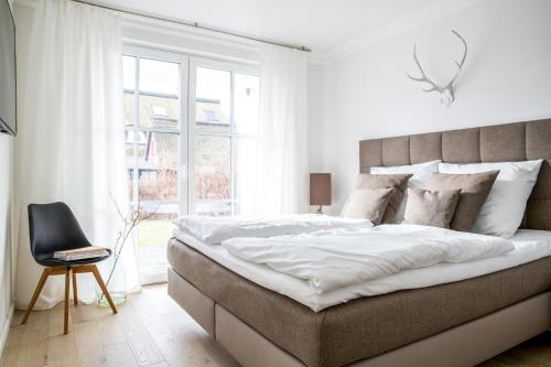 Groß KirrにあるFerienwohnung Duene 2_2の白いベッドルーム(大型ベッド1台、椅子付)