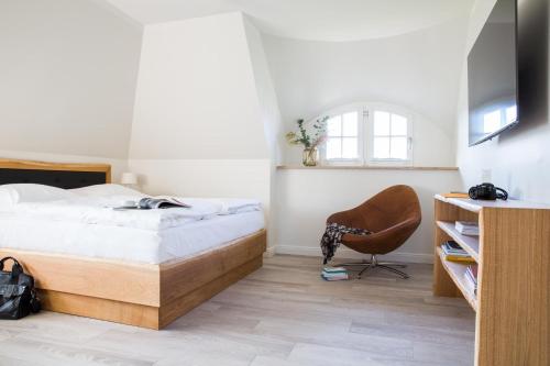 a bedroom with a bed and a chair at Ferienhaus Seeadler 3 in Fuhlendorf