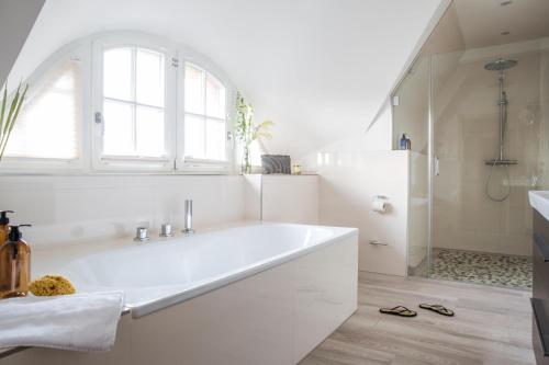 a white bathroom with a tub and a shower at Ferienhaus Seeadler 3 in Fuhlendorf