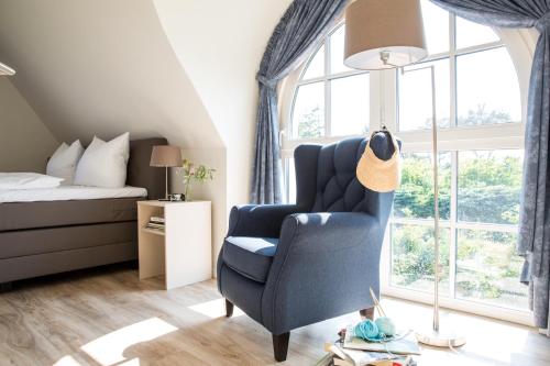 a bedroom with a blue chair and a bed at Ferienhaus Schilfrohrsaenger 51 in Fuhlendorf