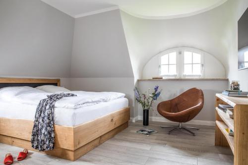 een slaapkamer met een bed en een stoel bij Ferienhaus Seeadler 11 in Fuhlendorf