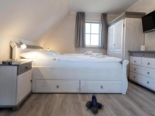 a bedroom with a large white bed and a window at Ferienhaus Schilfrohrsaenger 28 in Fuhlendorf