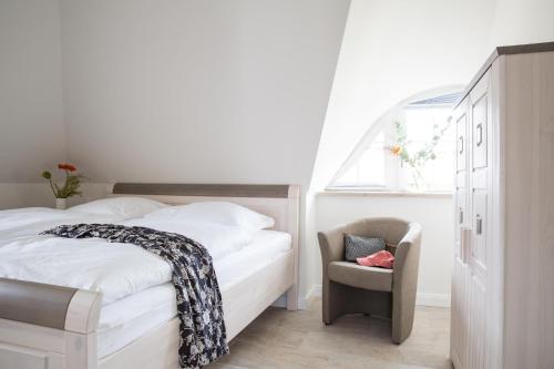 a bedroom with a bed and a chair and a window at Ferienhaus Seeadler 24 in Fuhlendorf