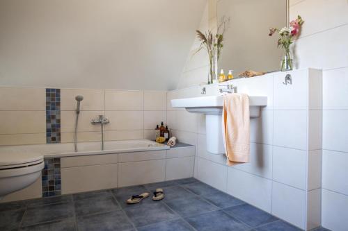 a bathroom with a tub and a sink and a toilet at Ferienhaus Schilfrohrsaenger 48 in Fuhlendorf