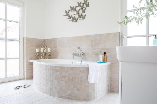 a bathroom with a bath tub in a room with windows at Ferienhaus Haubenlerche 14 in Fuhlendorf