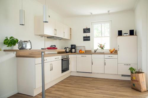 a white kitchen with white cabinets and a sink at Ferienhaus Schilfrohrsaenger 61 in Fuhlendorf