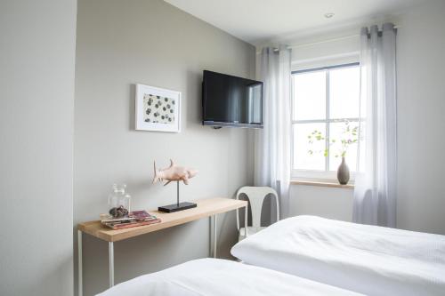 a bedroom with a bed and a desk and a television at Ferienhaus Seeschwalbe 44 in Fuhlendorf