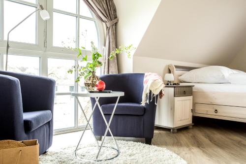 a bedroom with a bed and two chairs and a table at Ferienhaus Schilfrohrsaenger 30 in Fuhlendorf