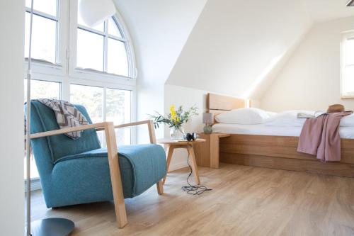a bedroom with a bed and a blue chair at Ferienhaus Schilfrohrsaenger 8 in Fuhlendorf